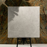 Close-up of Resina Grey matte porcelain tile showing detailed travertine texture, natural cracks, and 9mm thickness